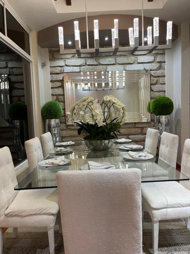 a dining room with a glass table and white chairs at Casa dentro del Campo de Golf in Comayagua