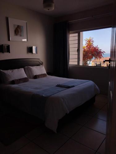 - une chambre avec un grand lit et une fenêtre dans l'établissement Illovo Views Holiday Apartment, à Kingsborough