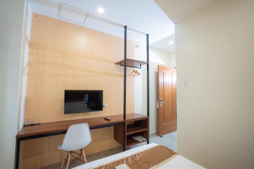 Schlafzimmer mit einem Bett und einem Schreibtisch mit einem TV in der Unterkunft Sundaze Dormitel in Naga