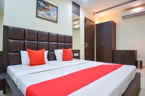 a bedroom with a large bed with red pillows at OYO Kings Inn in Ludhiana