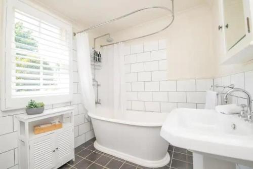 a white bathroom with a tub and a sink at Orana Cottage in Orange
