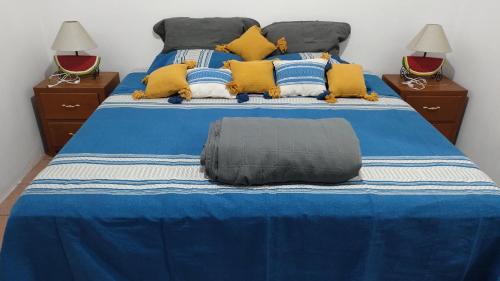 uma cama grande com lençóis azuis e brancos e almofadas amarelas em Casa la Arcada em Oaxaca de Juárez