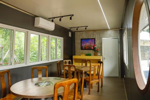 a dining room with tables and chairs and windows at Halo Retreat in Hòa Bình