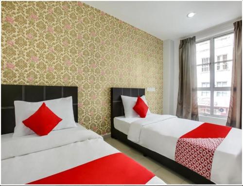 two beds in a room with red pillows at NS INN Hotel in Melaka