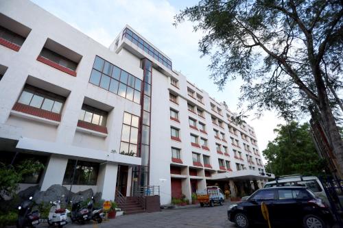 un edificio blanco con un coche aparcado delante de él en Breeze Residency en Tiruchchirāppalli