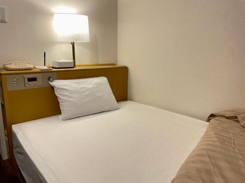 Bett mit weißem Kissen in einem Zimmer in der Unterkunft Sabae Daiichi Hotel in Sabae
