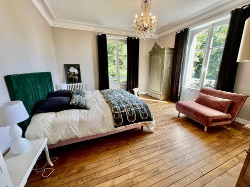 una camera con letto, sedia e lampadario a braccio di VILLA MEGUINELLE a Grand-Fougeray