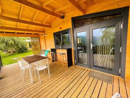 a wooden deck with a table and chairs and a sliding glass door at chalet nature sur la vallée de la Truyère in Neuvéglise