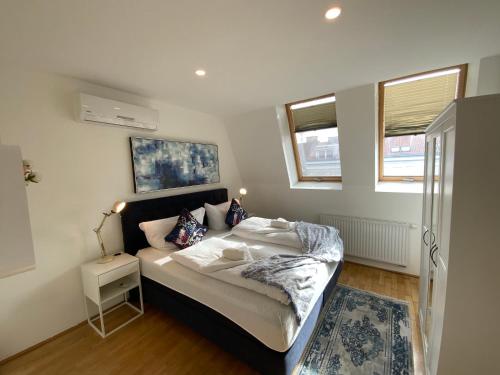 1 dormitorio con 1 cama con mesita de noche y 2 ventanas en Sunny & cozy Penthouse with Balcony DG5, en Viena