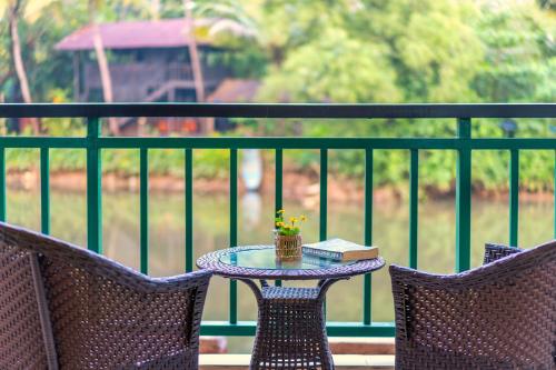 a table with a book on a balcony with two chairs at Mandrem Beach Resort, a member of Radisson Individuals Retreat in Mandrem