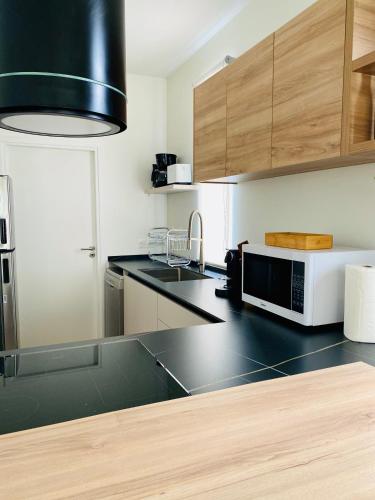 a kitchen with a black counter top with a microwave at Villa TE URA Beach in Paea