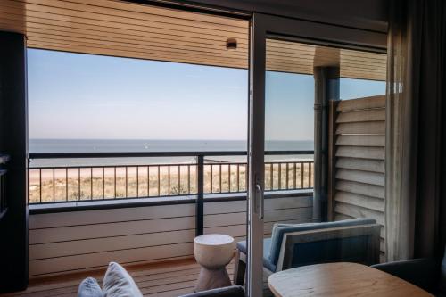 a room with a balcony with a view of the ocean at Strandhotel in Cadzand-Bad