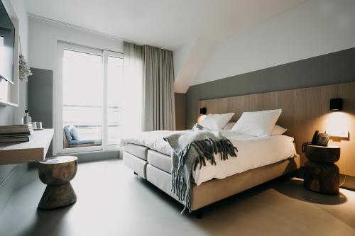 a bedroom with a large bed and a large window at Strandhotel in Cadzand-Bad
