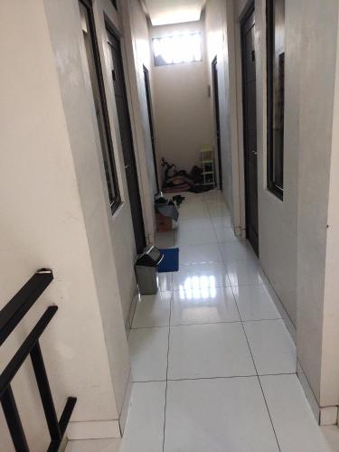 a hallway with white tiled floors and black doors at Rukost columbus in Karawang
