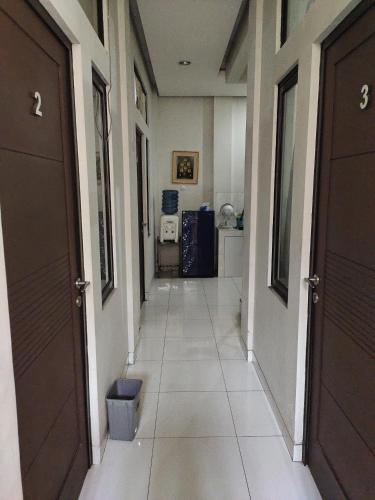 a hallway with two brown doors and a tile floor at Rukost columbus in Karawang