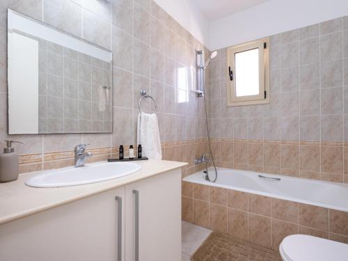 a bathroom with a sink and a tub and a mirror at Paradise Palms, 2bed Apt W Pool in Mandria