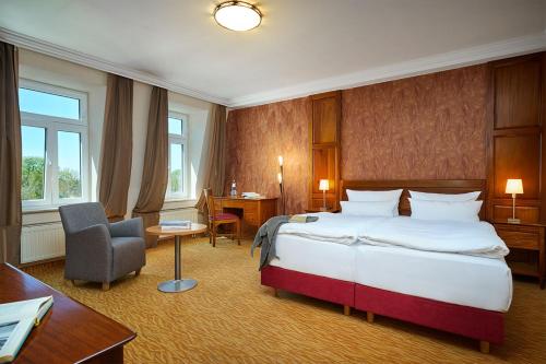 ツィノヴィッツにあるStrandhotel Preussenhofの大きなベッドとデスクが備わるホテルルームです。