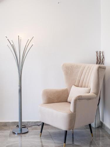 a chair in a living room next to a vase at Marble Heights, 2bed Luxury Apt in Kouklia