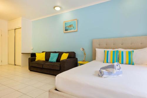 a bedroom with a large bed and a couch at Ramada Spacious Studio Apartment with Pool Views in Port Douglas