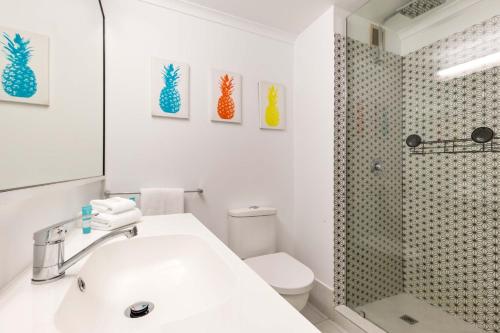 a bathroom with a white sink and a shower at Ramada Spacious Studio Apartment with Pool Views in Port Douglas