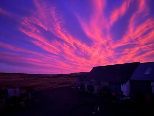 a sunset over a house in the middle of a field at Pentland view croft with a sea view in Melvich