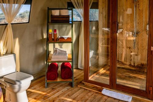 a bathroom with a shower and a toilet with red towels at Olmara Camp in Serengeti