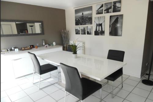 une salle à manger avec une table et des chaises blanches dans l'établissement Maison 3 chambres, salle de gym, jardin et terrasse, à Caen
