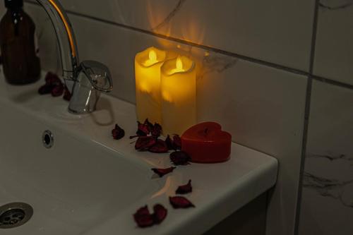 una candela seduta sopra un lavandino con rose di City Night Suites & Hotels a Çekme