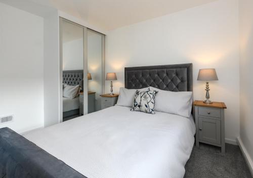 a bedroom with a large white bed and a mirror at Pebbles in Abersoch