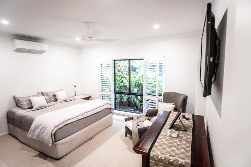 1 dormitorio con cama, mesa y ventana en Chez Brolga, en Port Douglas