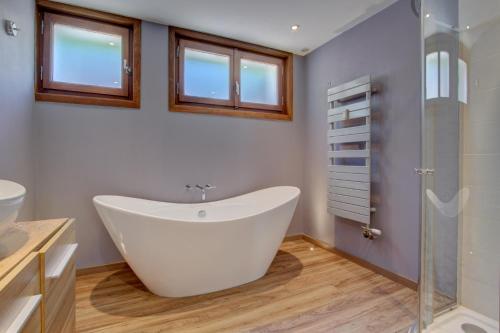 La salle de bains est pourvue d'une grande baignoire et d'une douche en verre. dans l'établissement Sabaudia Appartement deux chambres plein sud et à proximité du centre du village, à Morzine