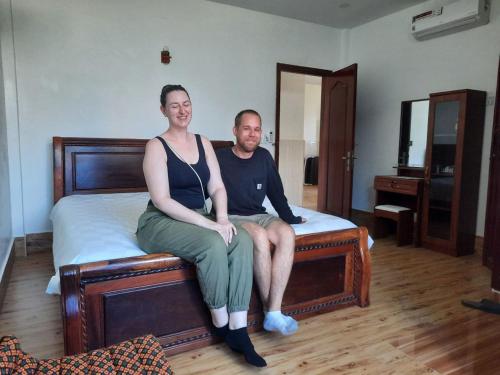 a man and a woman sitting on a bed at Realkhom Homestay in Siem Reap