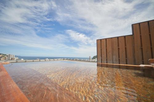 a swimming pool with the ocean in the background at Shin Kadoya in Atami