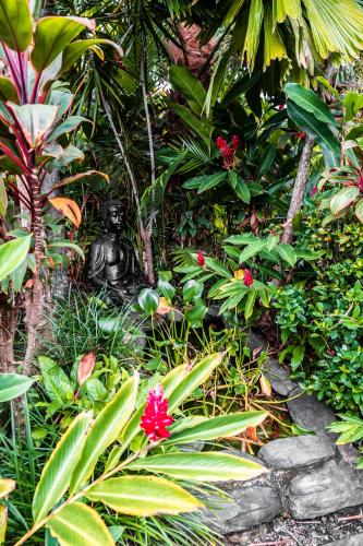 a statue in the middle of a garden with plants at Chez Brolga in Port Douglas