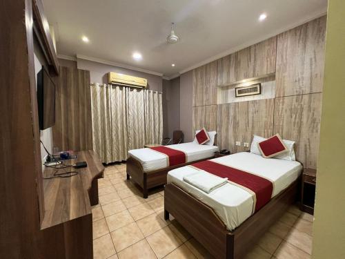 um quarto de hotel com duas camas e uma televisão em Hotel Bluemoon em Guwahati