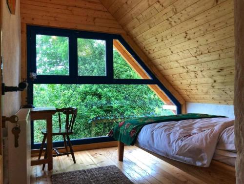 a bed in a room with a large window at La sat - Radu Dragu in Bertea