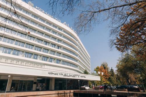 un gran edificio blanco con un cartel delante en Almaty Hotel en Almaty