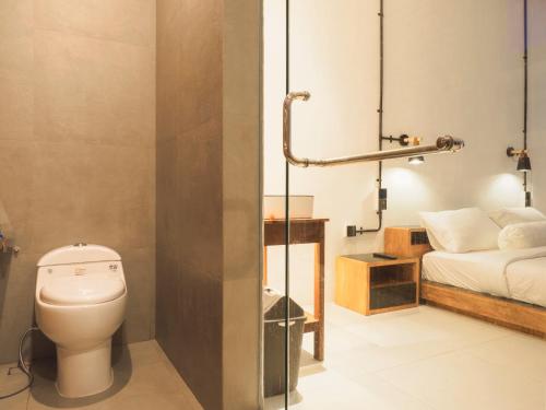 a bathroom with a toilet and a bed at SMARANALA in Nusa Dua