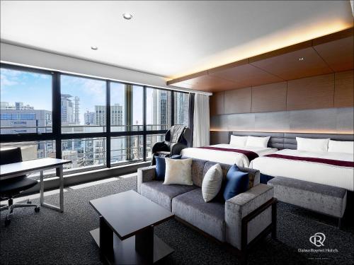 a hotel room with two beds and a couch at Daiwa Roynet Hotel KOBE-SANNOMIYA PREMIER in Kobe