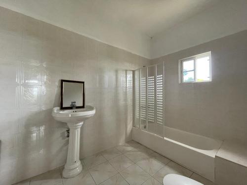 a white bathroom with a sink and a bath tub at The Retreat in Lyssons