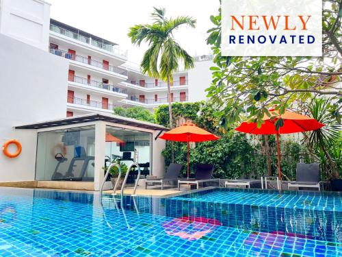 una piscina con ombrelloni accanto a un edificio di Citrus Patong Hotel by Compass Hospitality a Patong Beach