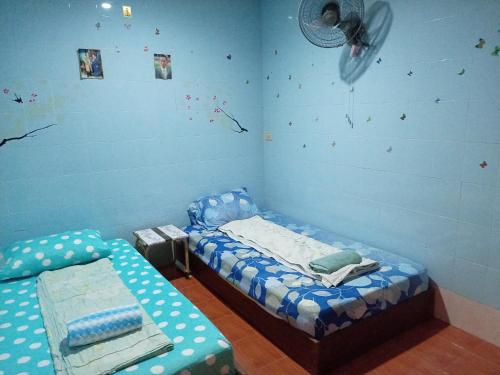 um quarto com 2 camas individuais e uma ventoinha em NP guesthouse em Trat