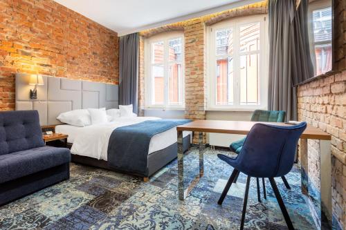 ポズナンにあるApartamenty Browar Luxury Old Town Poznań Check In 24hのベッド、テーブル、椅子が備わるホテルルームです。