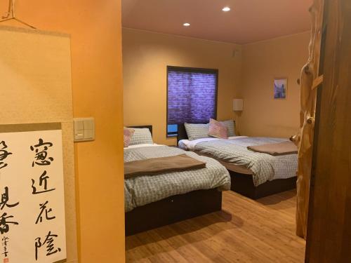 Giommachi的住宿－SAKARA KYOTO 桜香楽 京都，墙上写有亚洲文字的房间里,有两张床