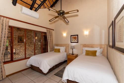 1 Schlafzimmer mit 2 Betten und einem Deckenventilator in der Unterkunft Kruger Park Lodge Unit No 441 with Private Pool in Hazyview