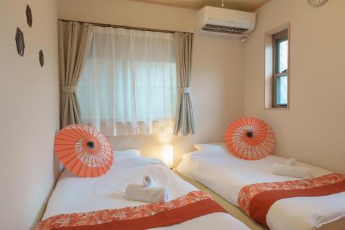 two beds in a room with orange and white umbrellas at 匯家•平和島ビル in Tokyo