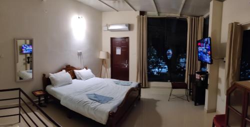 a bedroom with a bed and a flat screen tv at The Sunshine Bungalow in Bangalore