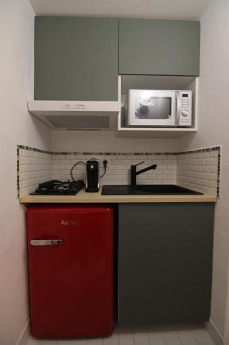 uma cozinha com um frigorífico vermelho e um micro-ondas em joli studio indépendant avec kitchenette em Sauveterre