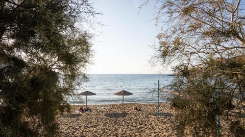 a beach with umbrellas and people sitting on the sand at Aniv Villa by the Sea in Kinion