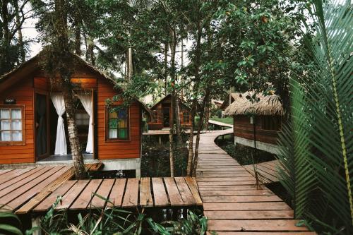 a wooden walkway leading to a cabin in the woods at Coco Camping Koh Kood in Ban Khlong Chao